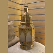 Lanterne Houda en laiton et verre coloré posée dans un intérieur