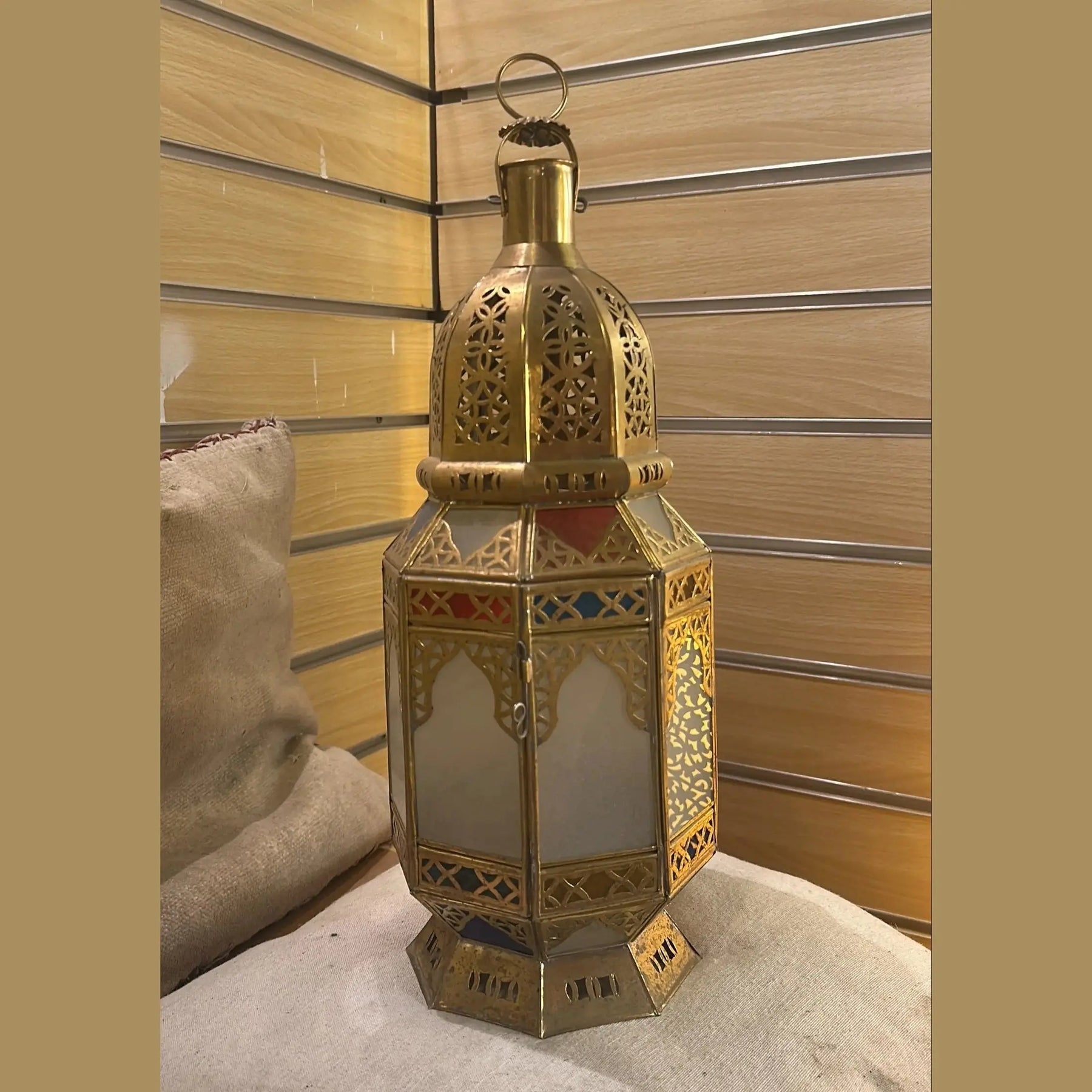 Lanterne Houda en laiton et verre coloré posée dans un intérieur